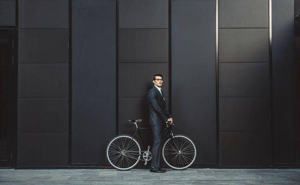 Young handsome man with business suit driving bycicle - Corporate businessman portrait, concepts about business, mobility and lifestyle - Фото, изображение