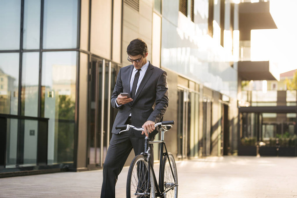 Young handsome man with business suit driving bycicle - Corporate businessman portrait, concepts about business, mobility and lifestyle - Photo, image