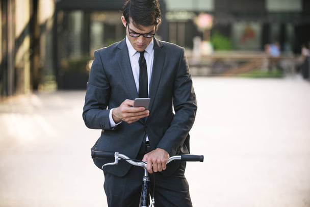 Young handsome man with business suit driving bycicle - Corporate businessman portrait, concepts about business, mobility and lifestyle - Foto, imagen