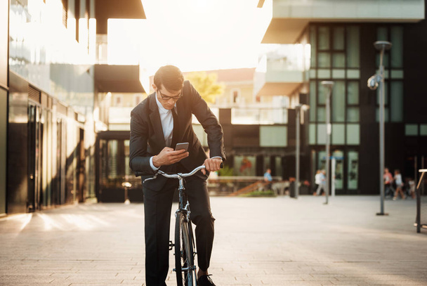 Young handsome man with business suit driving bycicle - Corporate businessman portrait, concepts about business, mobility and lifestyle - Foto, afbeelding