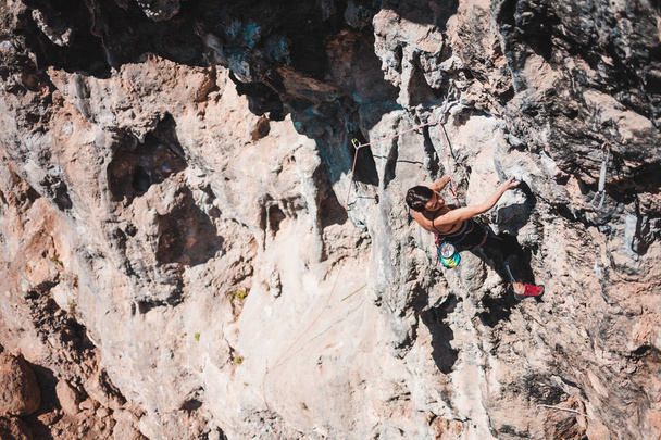 Una mujer sube a la roca. El atleta entrena en un relieve natural. Escalada en roca en Turquía. Una chica delgada se dedica a los deportes extremos. Un hobby activo. El escalador supera una ruta difícil
. - Foto, Imagen