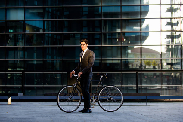 Young handsome man with business suit driving bycicle - Corporate businessman portrait, concepts about business, mobility and lifestyle - Фото, зображення