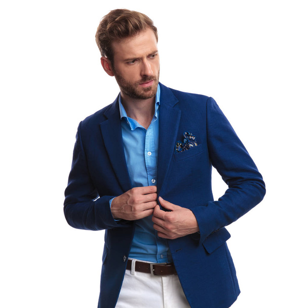 smart casual man looking something in his coat's inside pocket and looks to side on white background - Фото, изображение