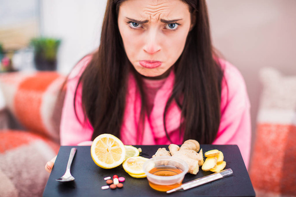 Close up sad sick woman keeps food and medicine on a table indoor - 写真・画像