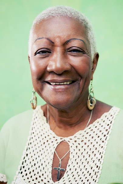 Porträt einer älteren schwarzen Frau, die auf grünem Backgr in die Kamera lächelt - Foto, Bild