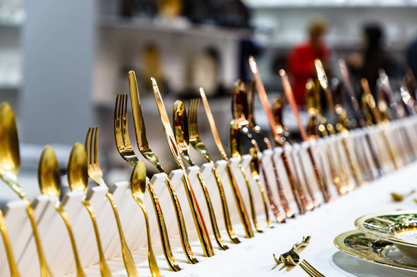 Copper, bronze and gold forks, knives and spoons on the store counter. - Фото, изображение