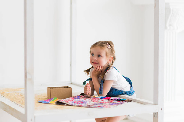 Malá holčička stojí v postýlce a vybere barvu postýlky na palety barvy interiéru - Fotografie, Obrázek