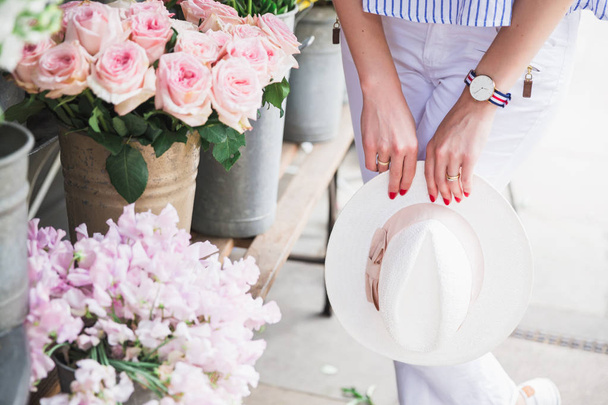 Photography of hat which stylish woman keeps near flowers outdoors - Φωτογραφία, εικόνα