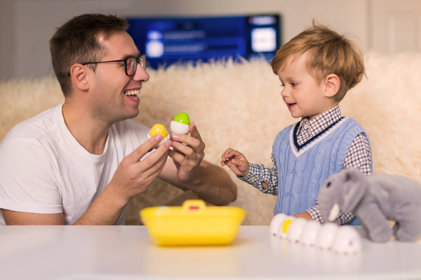 The young happy father with his little cute smiling son playing by different toys indoors - Foto, afbeelding