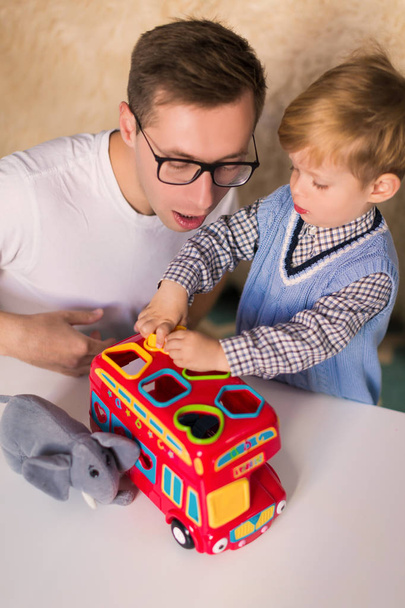 The young handsome father with his little cute son playing by developing toys indoors - Фото, зображення