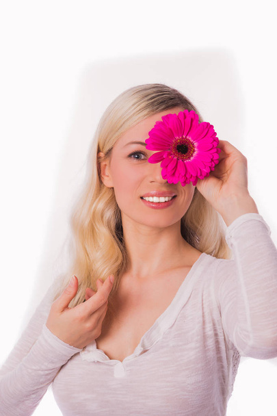 Portrait of young beautiful blonde woman who keeping rose flower on an eye against the white background - Foto, Imagem