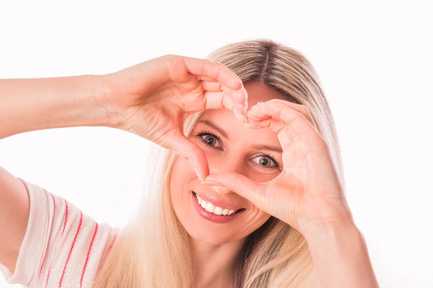 Портрет молодої красивої блондинки, яка посміхається і тримає руки біля очей на білому тлі
 - Фото, зображення