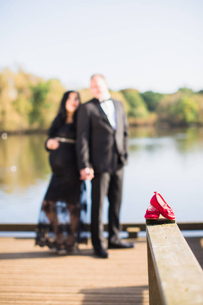Close up the red little footwear against the background of young couple - Fotografie, Obrázek