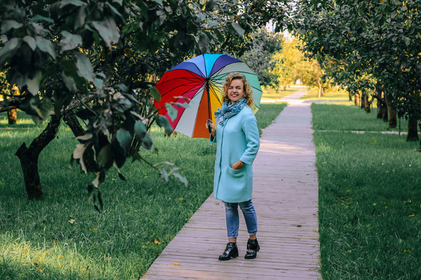 Jeune belle fille se promène dans le parc d'automne avec un parapluie coloré
. - Photo, image