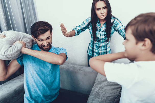 Family Fighting with Pillows and Have Fun at Home. Father and Son. Upset Mother. Have Fun Indoor. Parenthood Concept. Pillow Fight. Unshaved Young Man. Family at Home. Happy Family. - Foto, afbeelding