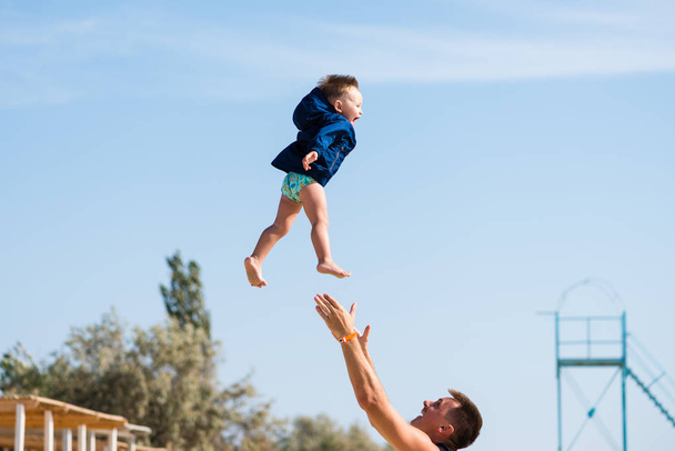 glücklich lächelndes Kleinkind fliegt aus den Händen nach oben - Foto, Bild