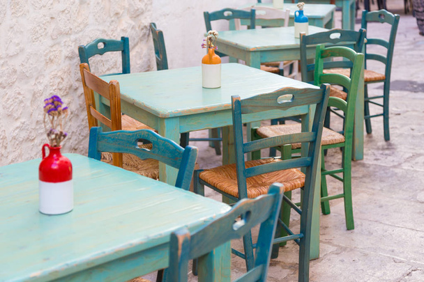 Mesas al aire libre vintage de madera verde y sillas de un restaurante italiano en Locorotondo, Puglia, Italia
 - Foto, Imagen