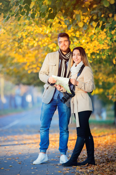 Young travel couple with map and camera in city autumn alley.  - Foto, afbeelding