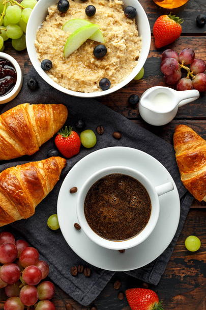 Gezond ontbijt geserveerd met koffie, sinaasappelsap, croissants, ei, granen, havermout en fruit - Foto, afbeelding
