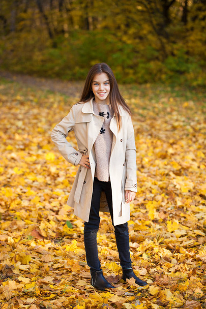 Happy young little girl in beige coat in autumn park - Fotoğraf, Görsel