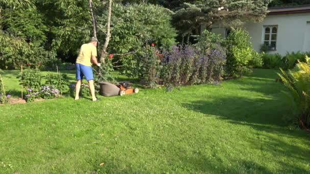 hombre trabajar con cortador de hierba en jardín de flores verde cerca de casa. 4K
 - Imágenes, Vídeo