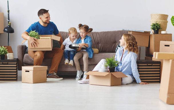 onnellinen perhe äiti isä ja lapset muuttavat uuteen asuntoon ja purkavat laatikon
 - Valokuva, kuva