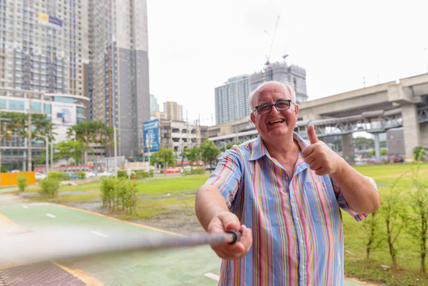 Избыточный вес старший турист исследуя вокруг города Бангк
 - Фото, изображение