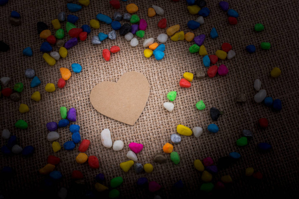 Paper heart amid colorful pebbles on canvas ground - Photo, Image