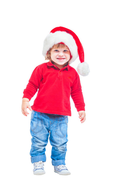 Christmas. A little boy in a Santa hat, in a red jacket and blue jeans. Isolated on white background. - Foto, Imagem