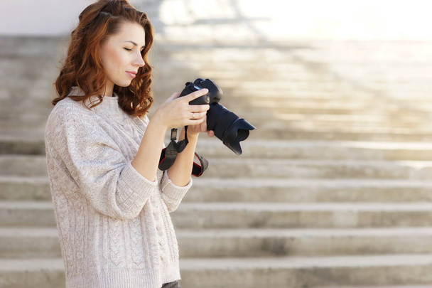 bela jovem menina de cabelos vermelhos com uma câmera tira fotos no espaço street.copy
 - Foto, Imagem