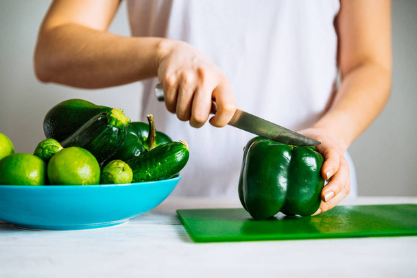 donna in t-shirt bianca tagliata insalata su tavola verde. concetto di cibo sano
 - Foto, immagini