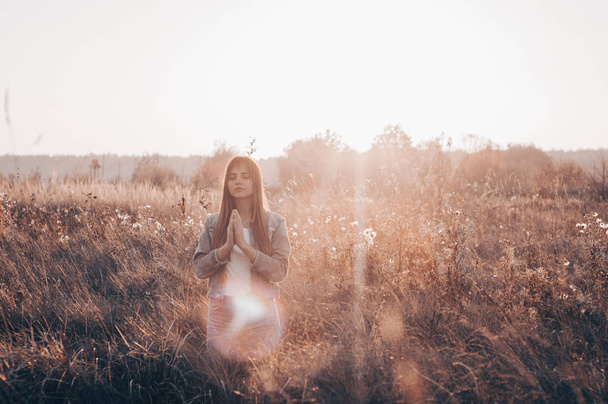 girl closed her eyes, praying outdoors, Hands folded in prayer concept for faith, spirituality and religion. hope, dreams concept. - Photo, Image