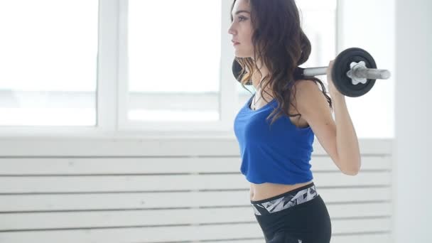 fitness, sport, entraînement et mode de vie concept - Jeune femme avec haltère flexion des muscles dans la salle de gym intérieure blanche
 - Séquence, vidéo