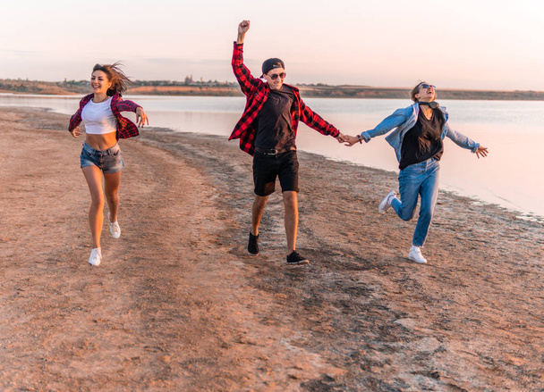 jonge hipster vrienden op het strand runnen samen - Foto, afbeelding