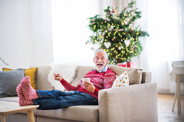 Un uomo anziano con una tazza di caffè a casa nel periodo natalizio
. - Foto, immagini