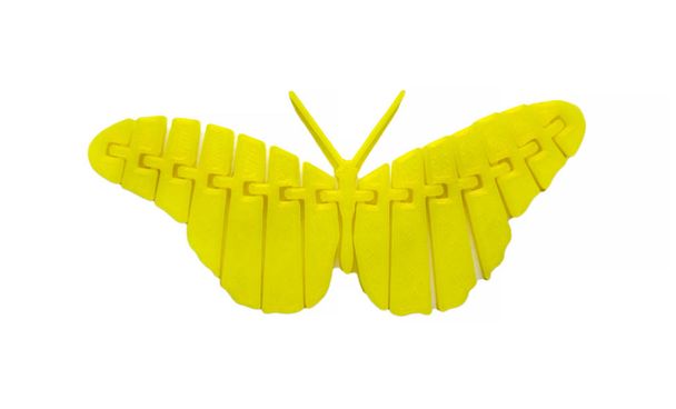 Φωτεινό κίτρινο αντικείμενο σε σχήμα πεταλούδας παιχνίδι τυπωμένο σε 3d εκτυπωτή - Φωτογραφία, εικόνα