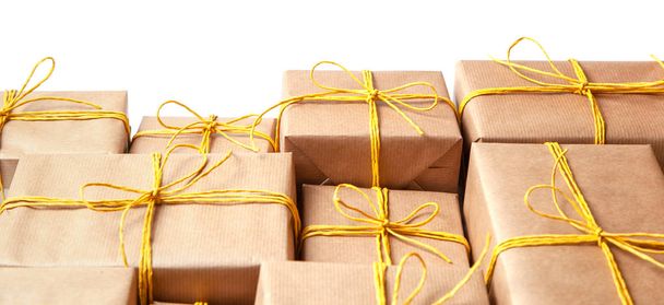 Gift boxes in festive packaging with golden yellow bows isolated on white. Delivery of gifts by the postal cargo service - 写真・画像