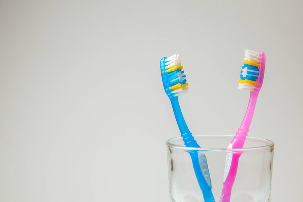 Dos dentaduras postizas de color rosa y azul en vidrio sobre fondo gris. El concepto de cepillos de dientes para pareja, residencia conjunta
 - Foto, Imagen