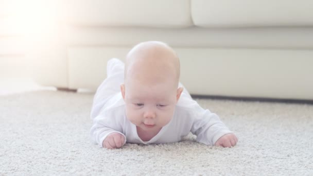 Lindo bebé divertido acostado en una alfombra beige
 - Imágenes, Vídeo