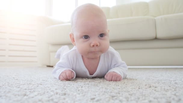Lindo bebé divertido acostado en una alfombra beige
 - Imágenes, Vídeo