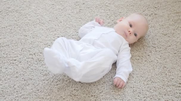 süßes lustiges Baby liegt auf einem beigen Teppich - Filmmaterial, Video