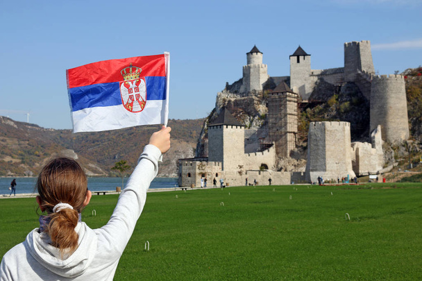 una chica con bandera serbia mira la fortaleza de Golubac
  - Foto, Imagen