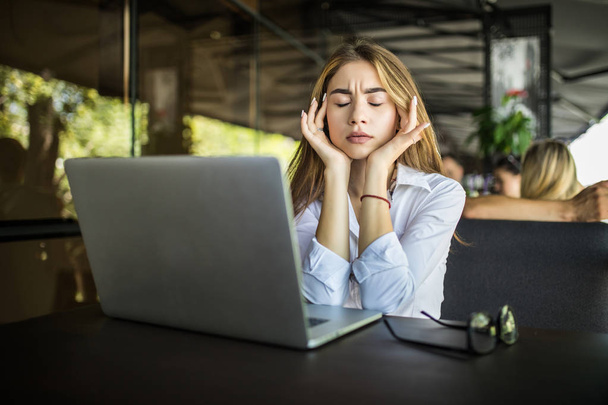 Estilo de vida independiente mujer trabajadora y computadora portátil que dolor de cabeza infeliz en el trabajo en la cafetería
 - Foto, Imagen