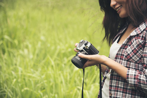 Hipster jolie femme regardant sur sa photo de l'écran de l'appareil photo après prendre une photo sur une prairie verte
. - Photo, image