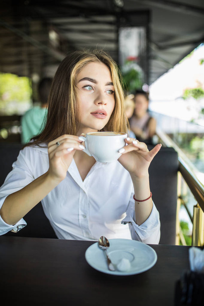 コーヒーを飲みながらカフェの若い女性 - 写真・画像