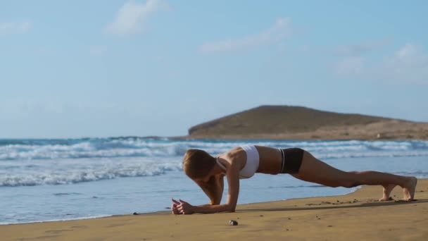 日没時にビーチに板の位置で美しいスポーティな女性の側面図. - 映像、動画