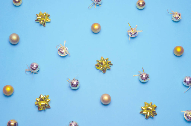 Christmas pattern. Golden bells, balls and bows on pastel blue background.  Flat lay top view.  - Photo, Image
