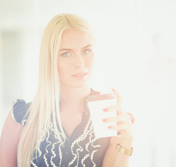 Businesswoman holding a cup of coffee standing in office . - Φωτογραφία, εικόνα