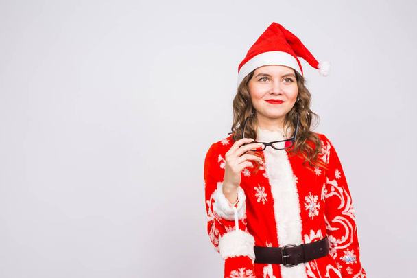 Christmas, holidays and people concept - young woman in santa suit took off glasses on white background with copy space - Fotó, kép