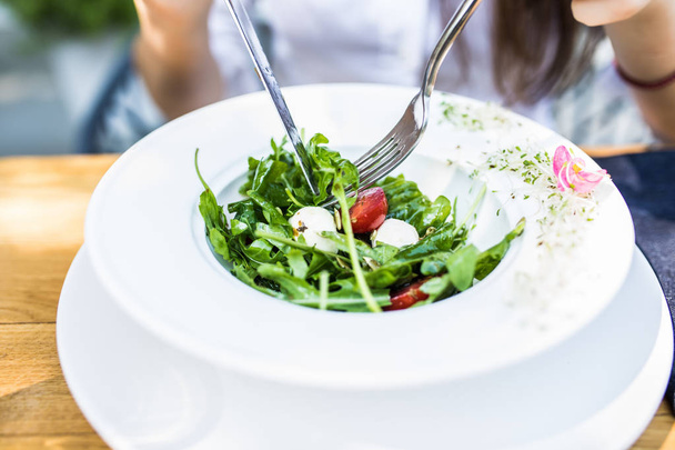 Close up attractive woman hand holding fork and spoon to eating vegetable salad with a cup of coffee at lunch in cafe. Healthy and vegetarian food. - Φωτογραφία, εικόνα